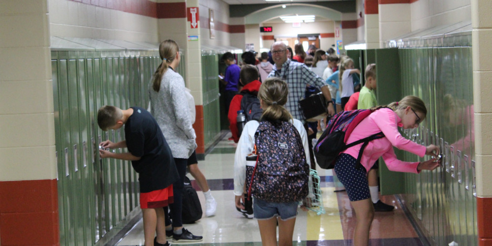 Girl walking down hallway with students at lockers