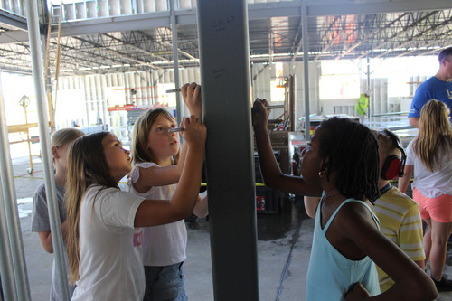 Adults and kids drawing on a structural pillar inside a building
